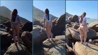 Naturista Eva Moderninha, jovem, dando uma caminhada sem roupa nas pedras